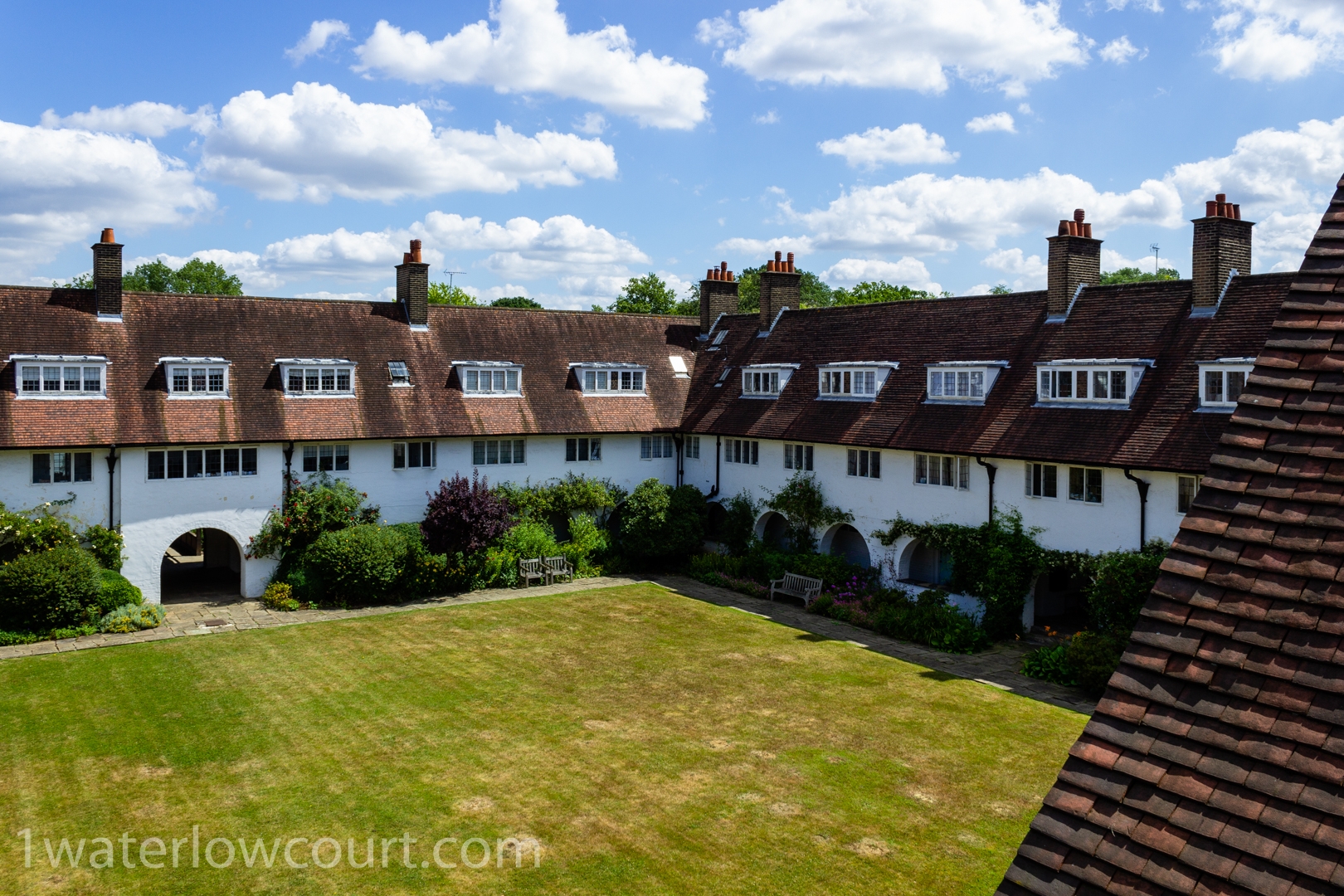 A bird’s eye view of the central garden and cloisters of Waterlow Court. Waterlow Court is an Arts & Crafts Grade II* listed building, designed by M. H. Baillie Scott, 1909, and located in Hampstead Garden Suburb, London NW11 7DT. Flat 1, a one-bedroom, ground-floor flat, is for sale. Listed on Rightmove and Zoopla.